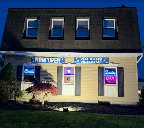 Psychic Ashley's studio in Rockaway at dusk — neon signs glowing, walk-ins welcome